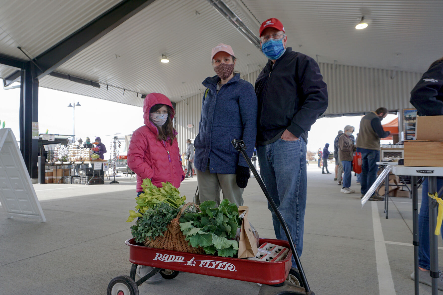 Carlann and her parents stand with their radio flyer wagon of groceries